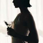 a silhouette of a woman holding a martini