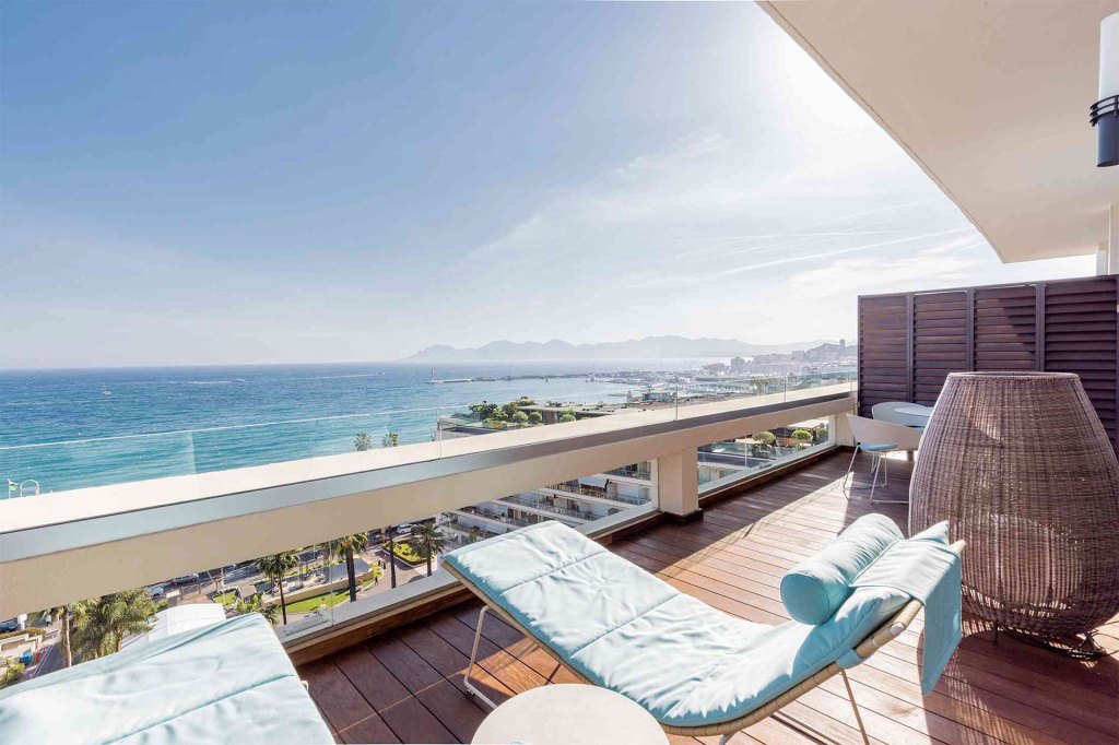 A serene ocean view from a balcony with comfortable lounge chairs.