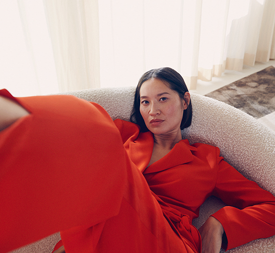 Woman in orange dress sitting in a white chair with her legs propped up