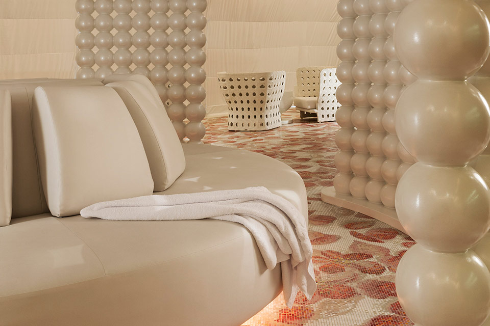 Mondrian Doha spa area with a white circular couch, red and white floral floors and white beaded walls.