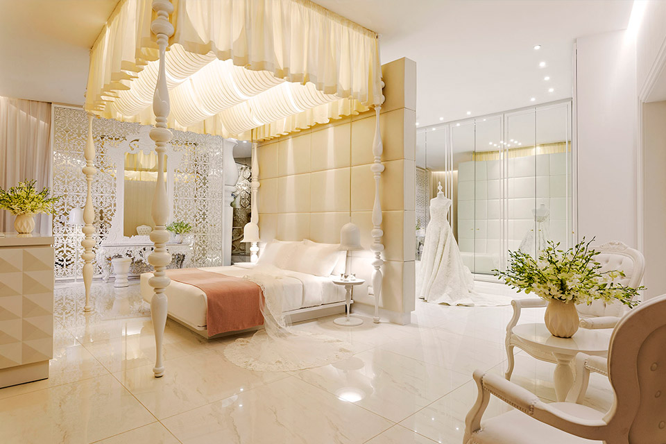 Opal suite at Mondrian Doha with a king bed with a white canopy, and a bridal dress on display in a room with mirrors.