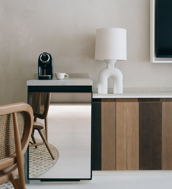 Hotel room silver mini fridge with console with a white table lamp on top