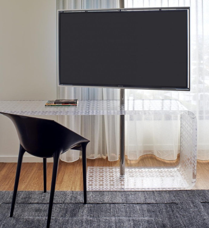 Large TV with a clear table and black, plastic chair