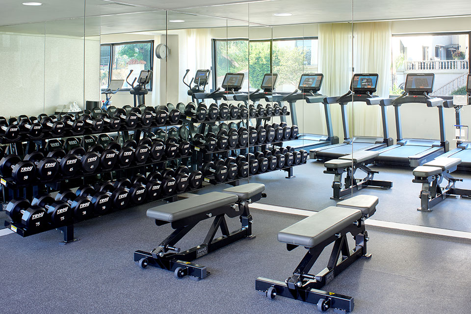 Fitness center with a large mirror on the wall, dumbbells, treadmills and weight lifting benches.