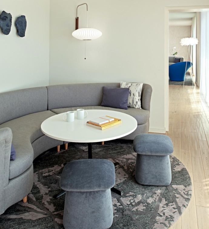 Corner with a grey wraparound couch, table and chairs