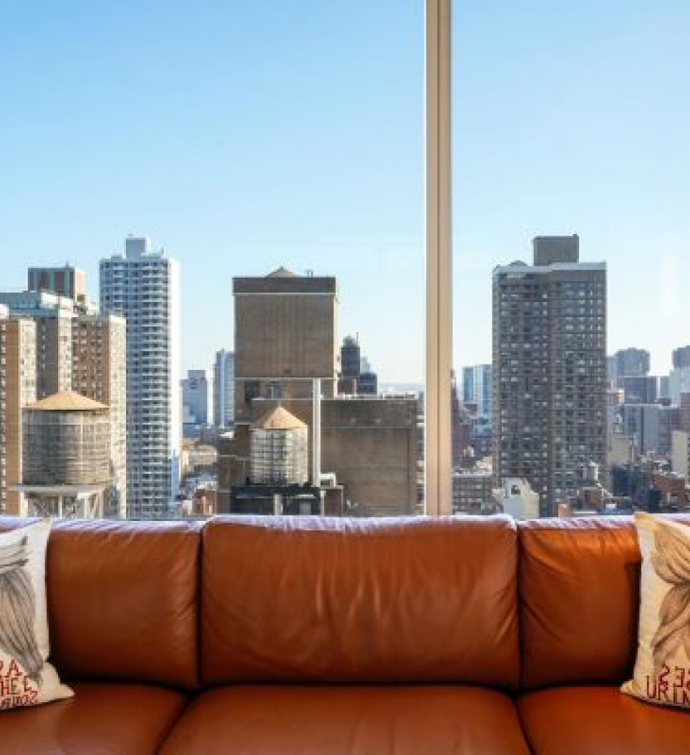 a tan leather couch up against a window with a spectacular skyline view