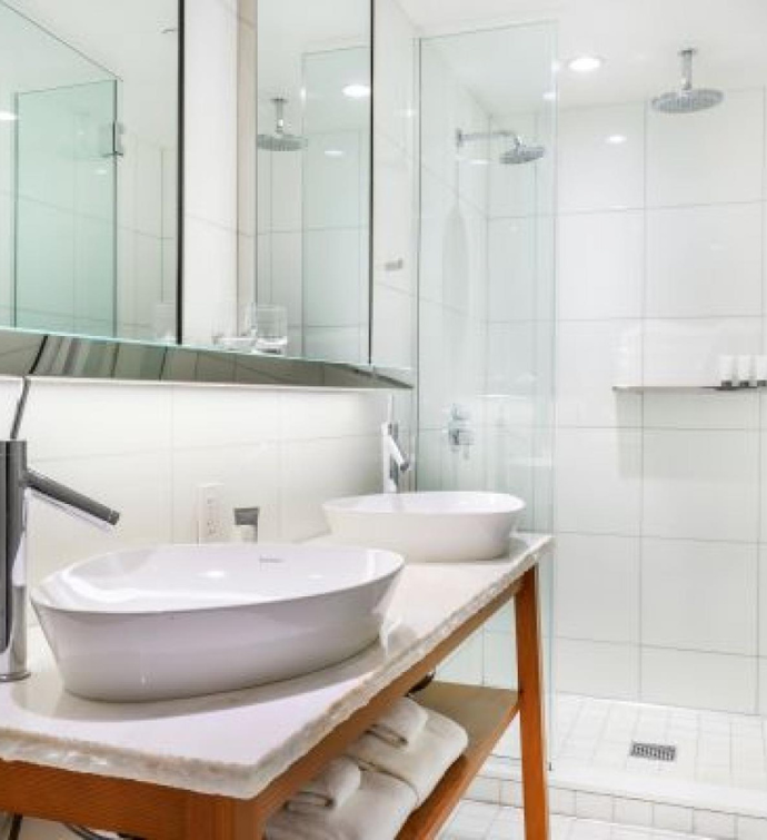 a bright and clean bathroom with a waterfall shower and two sinks 