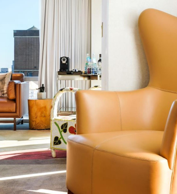 a living are with two tan leather chairs in the foreground and natural light