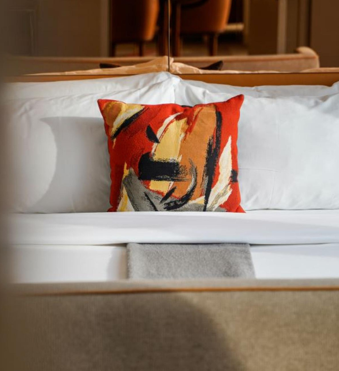 a close up of a made king bed with a modern decorative pillow on top