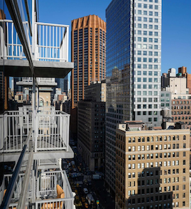 Multiple stacked balconies on a city building with sky scrapers and other buildings in the background