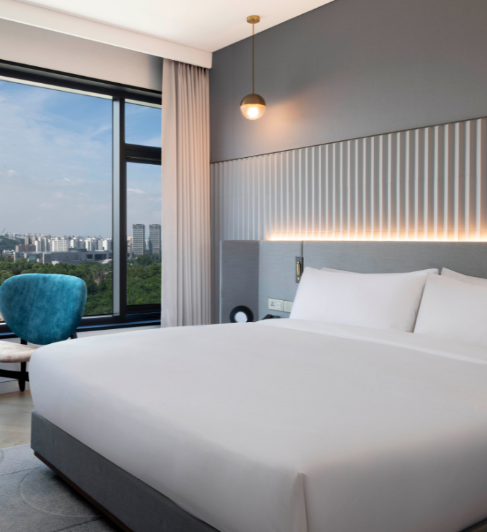 a bedroom with a king bed, a blue chair next to floor to ceiling windows