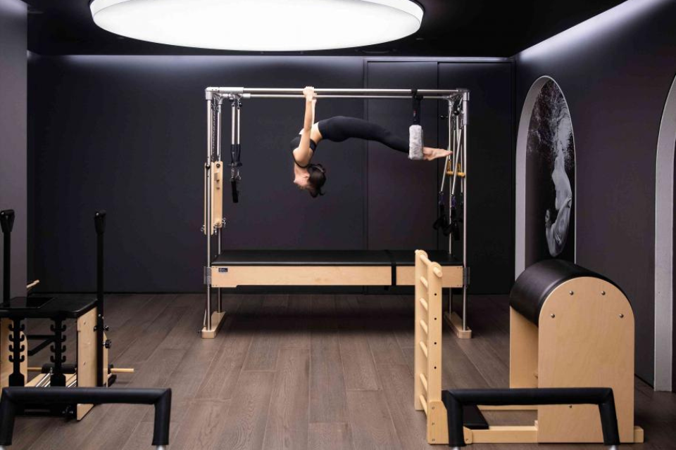 a woman hanging from a pilates machine in a room full of pilates equipment