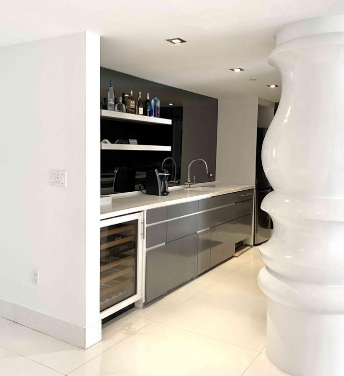 Kitchenette with silver appliances and large white column in the middle of the room