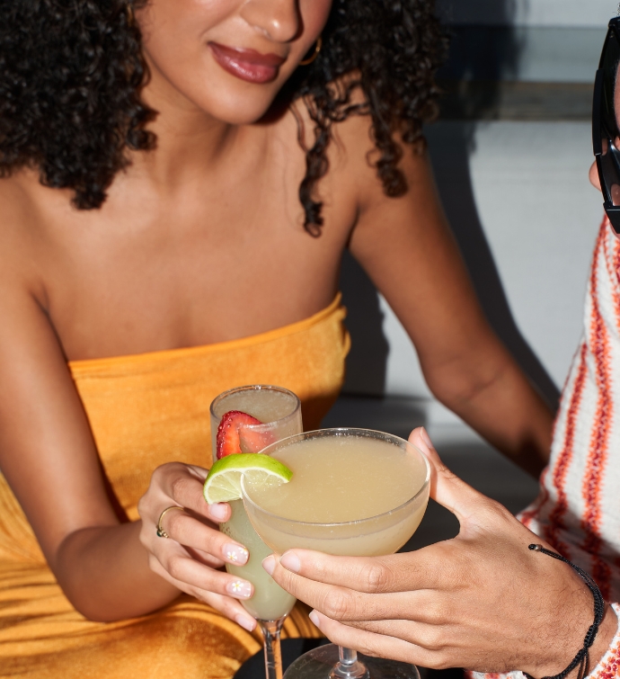 Woman in an orange dress doing cheers with a cocktail