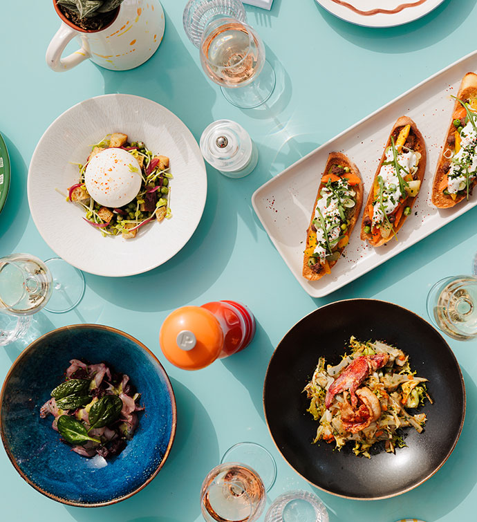 A light blue table set with an array of fresh Italian dishes from Hyde Beach Cannes, photographed from above