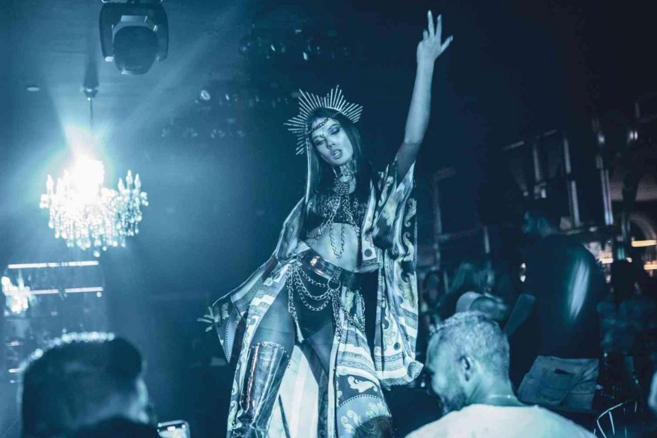 Woman in a costume and a crowd with her hand up dancing on stage at Black Orchid Doha