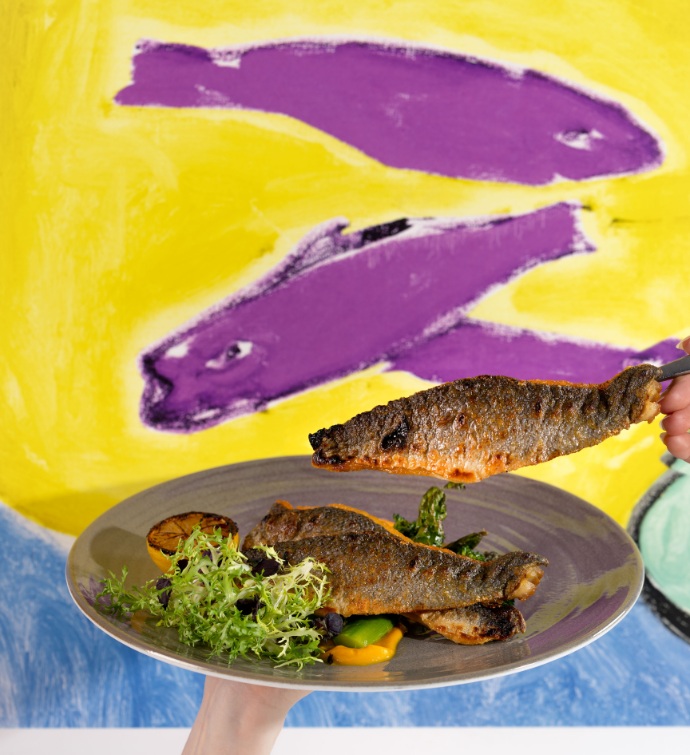 Plate of fish with a colorful fish mural in the background