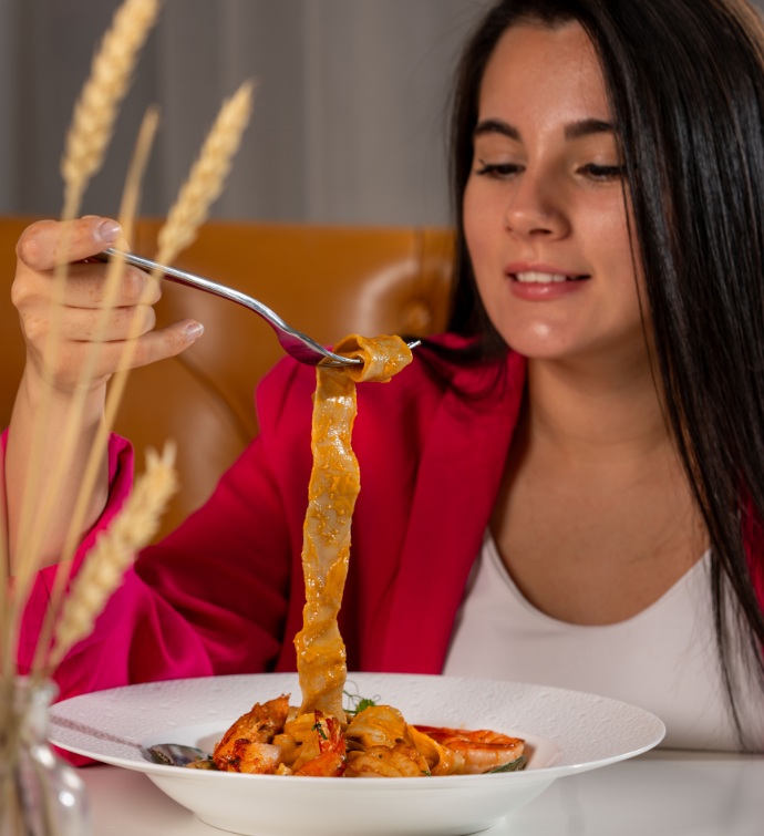 Woman in a red blazer eating pasta