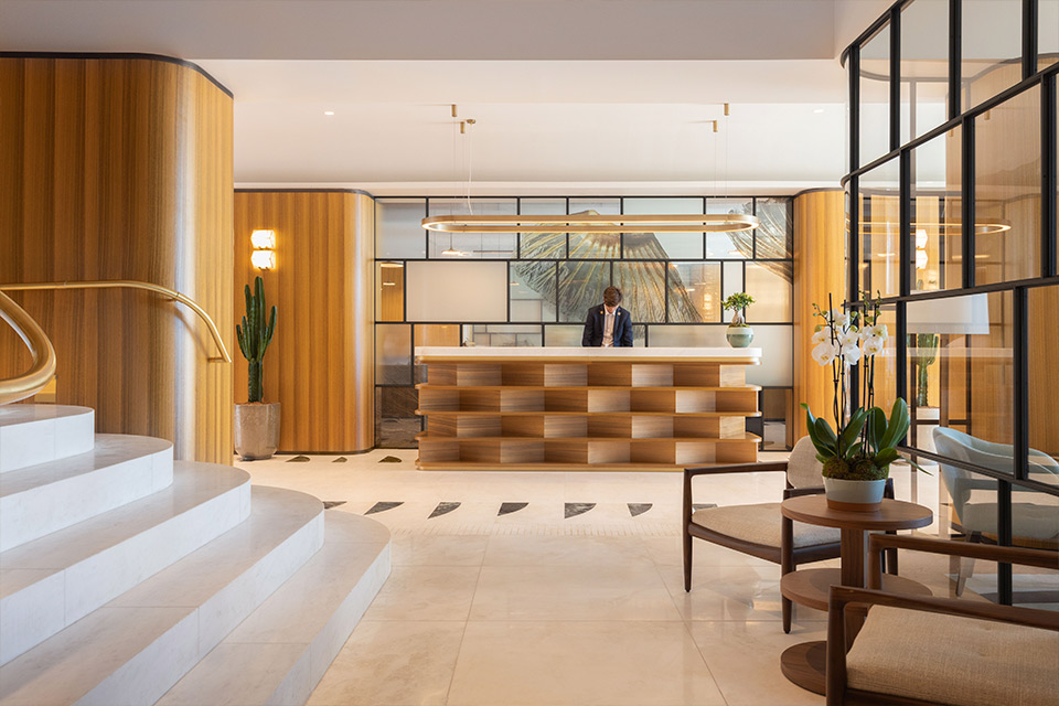 Hotel lobby with reception desk, modern decor, comfortable seating, and elegant lighting fixtures.