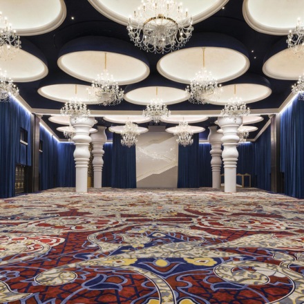 Large ballroom space with blue curtains on the walls and chandeliers