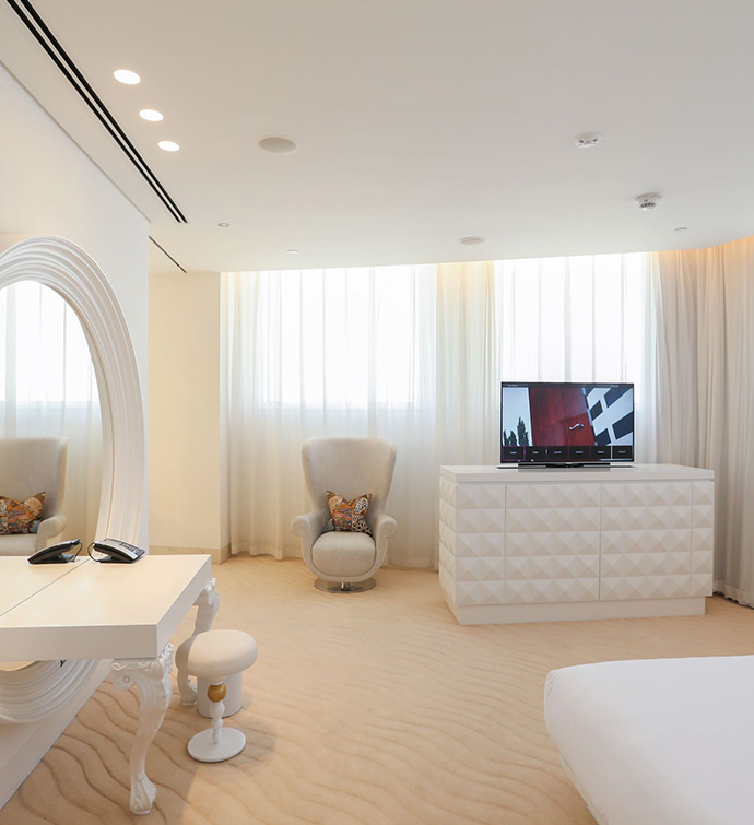 A white bedroom with a large mirror and a desk.