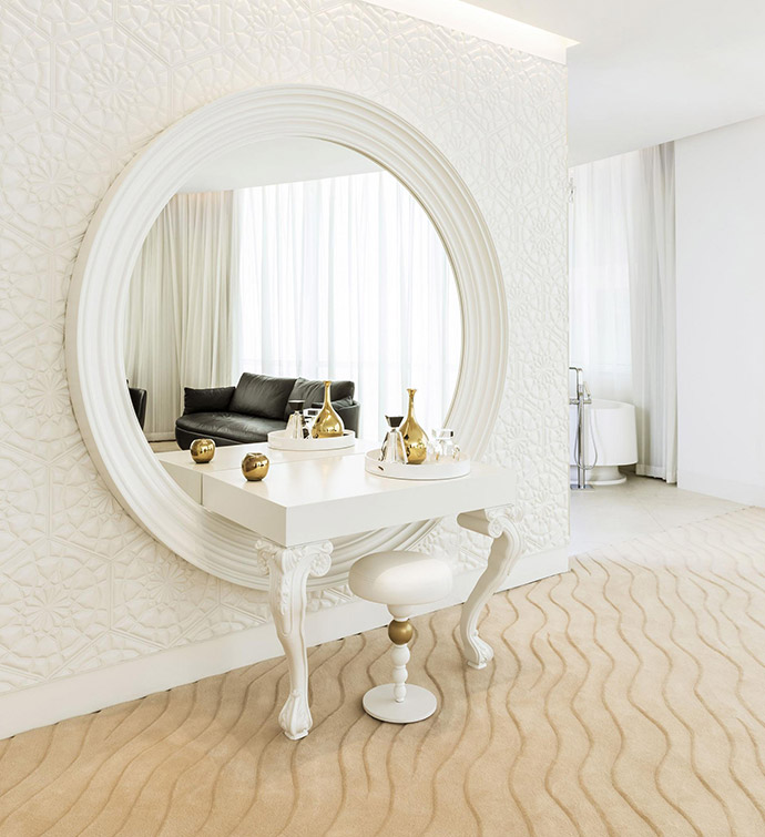 A white vanity with a mirror and a stool.