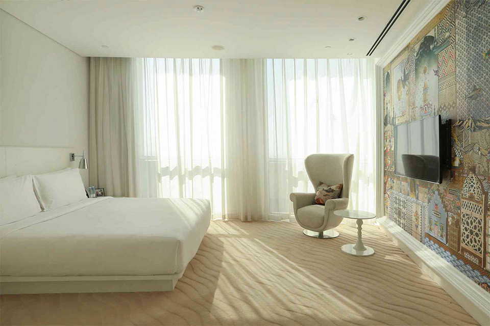 A hotel room with a spacious bed and a captivating wall mural.