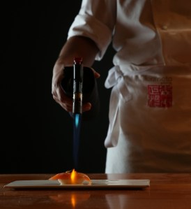 Morimoto Doha sushi chef torching a piece of sashimi