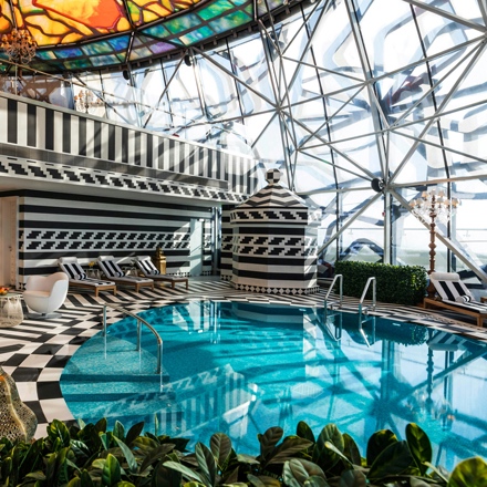 Mondrian Doha spa round pool with black and white floors and walls, and a stained glass ceiling.