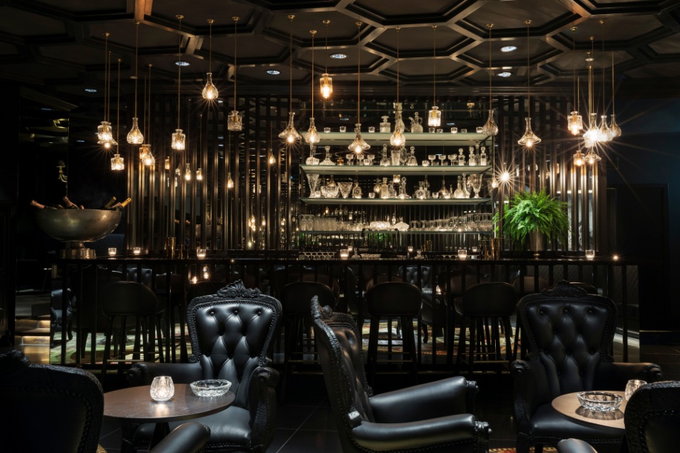 Interior of Smoke and Mirrors Doha with black leather seating and a long bar 