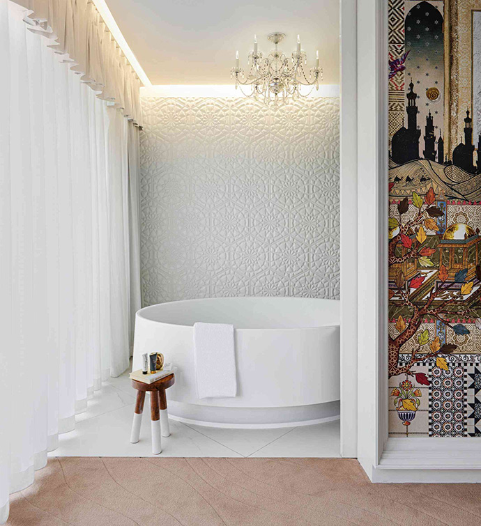 A bathroom with a white tub and a wall adorned with vibrant tiles.