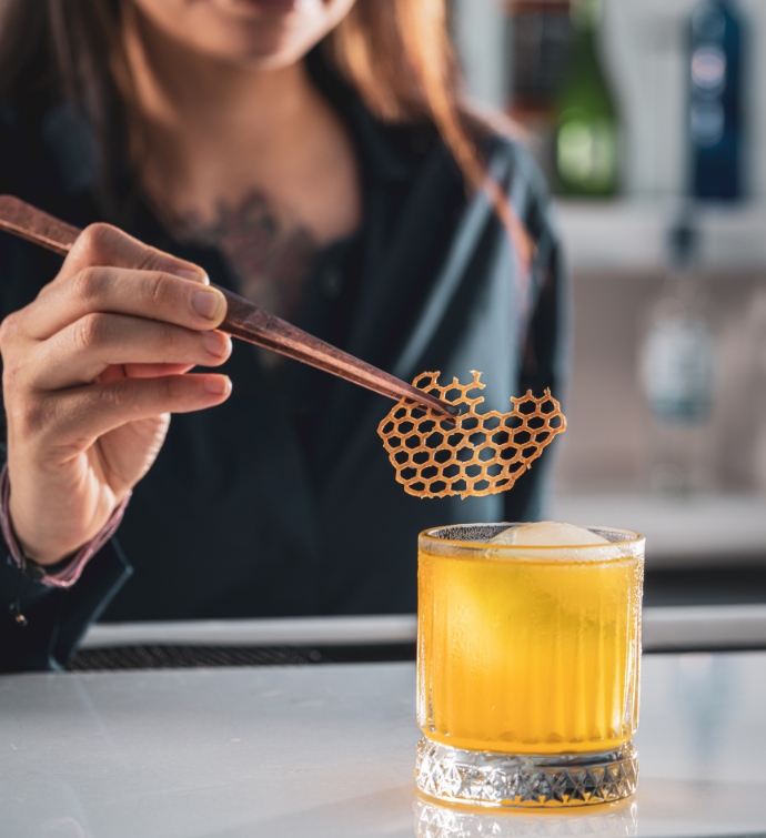 Bartender putting a garnish on an orange cocktail 