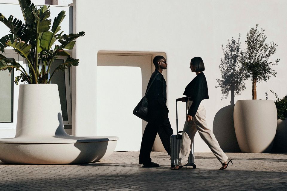 Two people walking with luggage in front of Mondrian Ibiza