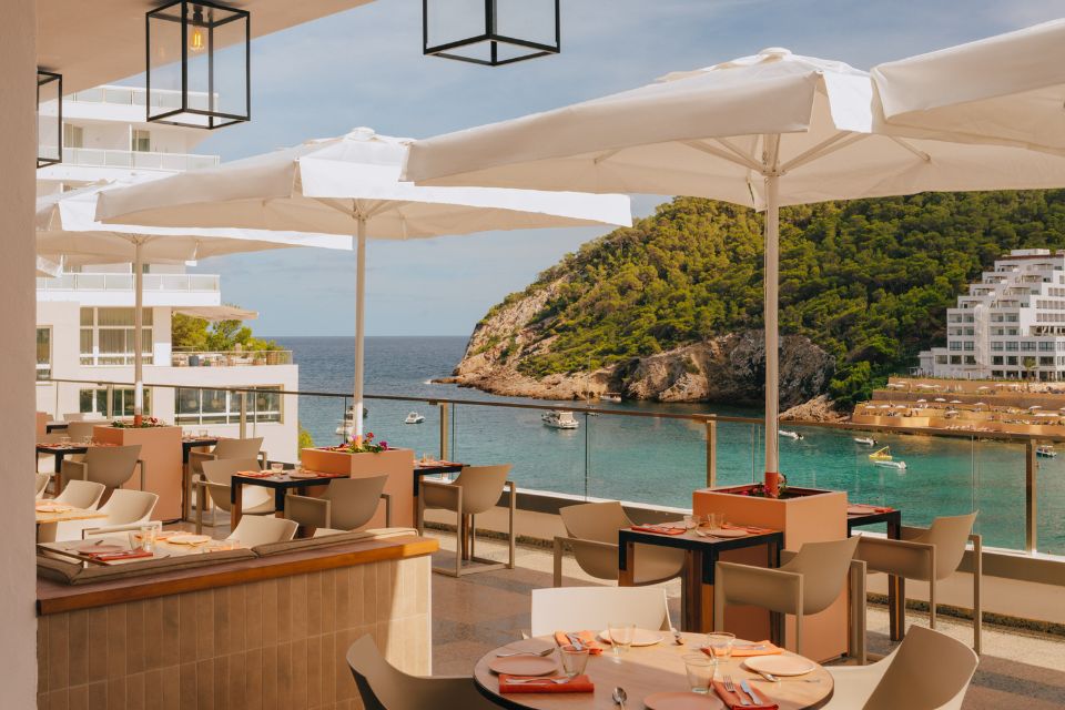 Patio with umbrellas, tables, and ocean in the background