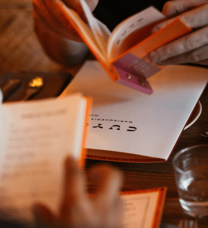 an orange and pink cuyo menu being opened up on a table