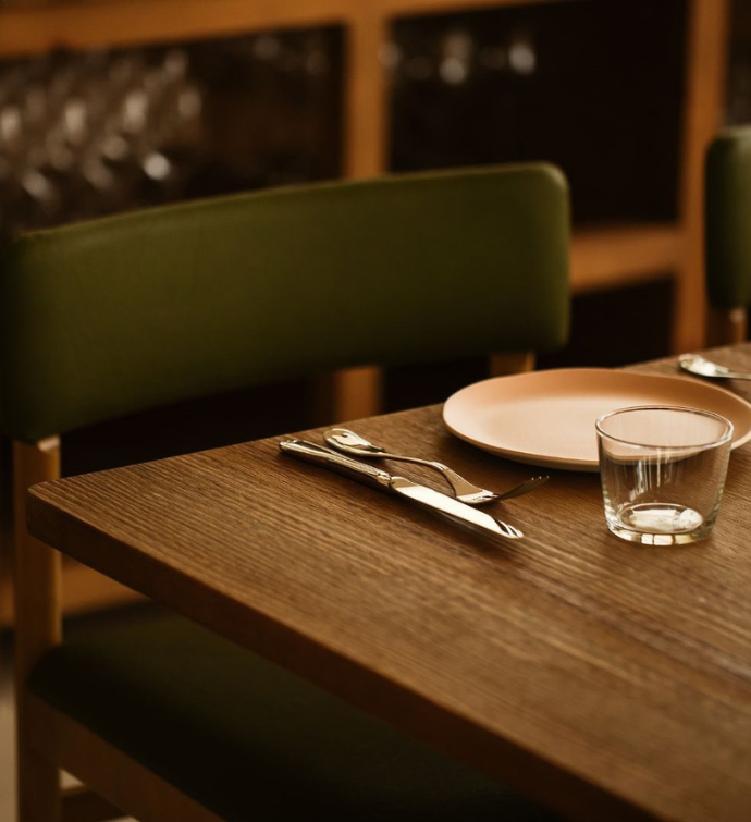 a green leather chair pulled up to a table which has been set 