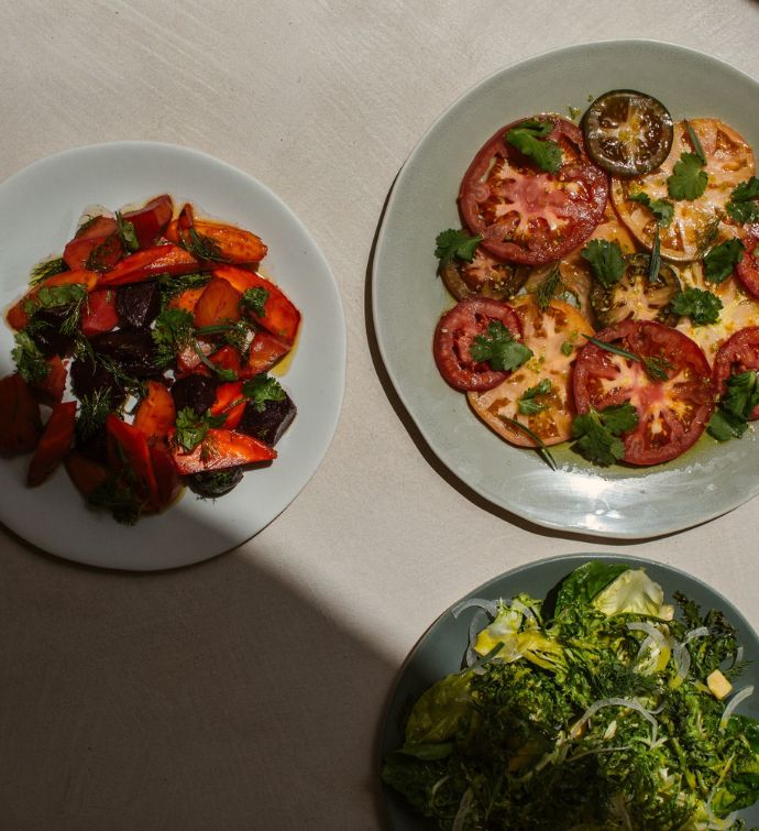 Three plates of vegetables on a white tabletop