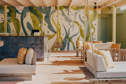 Multiple outdoor sofas and chairs over a covered patio with a decorative green and blue wall in the background