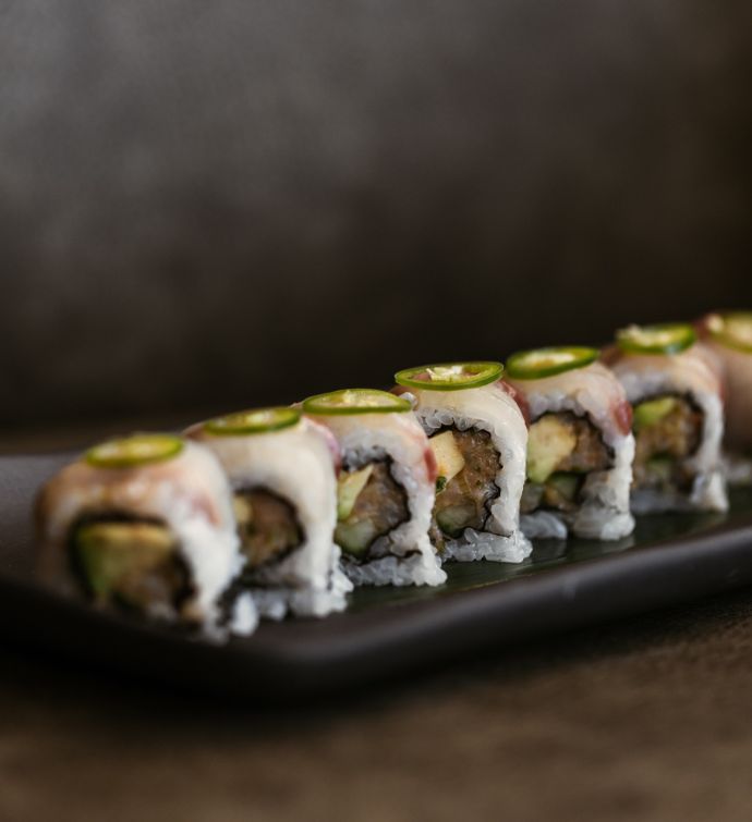 Sushi roll on a long black plate with dark background