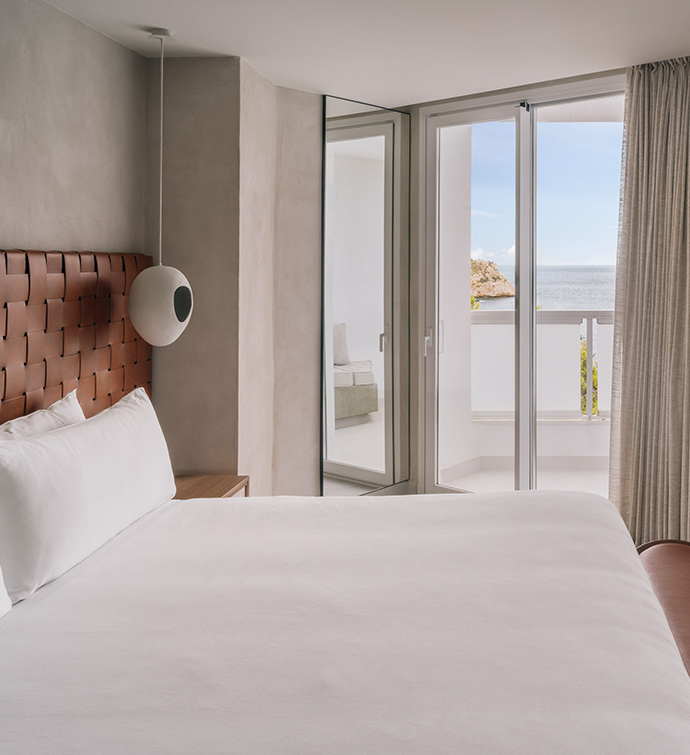 A spacious bedroom with a bed overlooking the ocean.