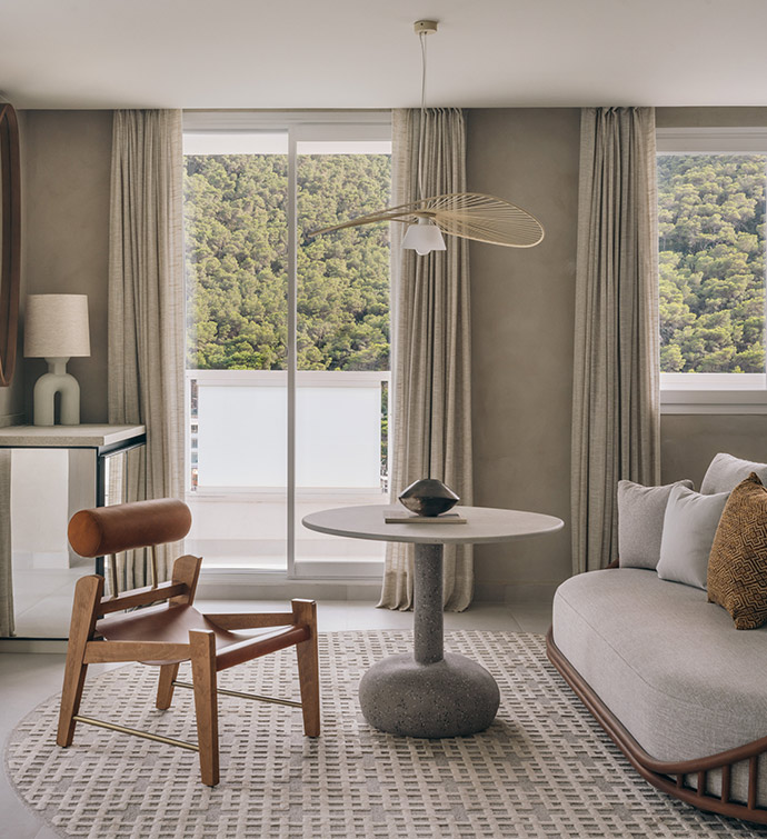 A cozy living room with a round table, fan, a couch and balcony.