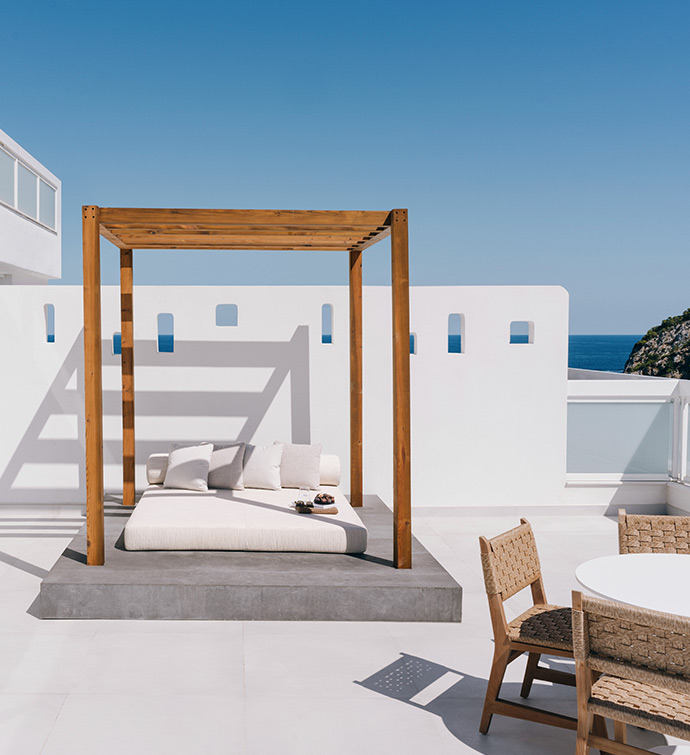 White patio with wooden daybed and table.