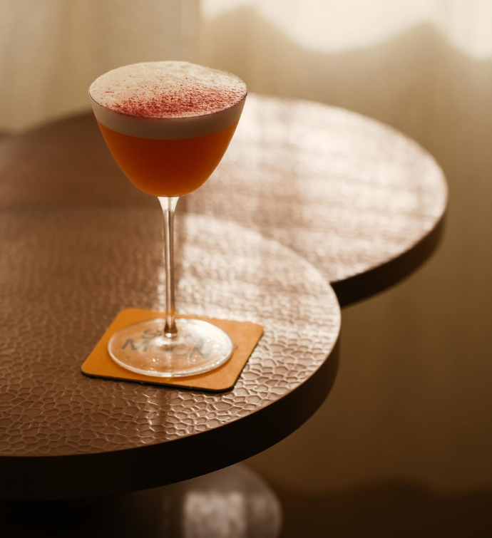 a sophisticated red cocktail in a tall glass with on an orange napkin