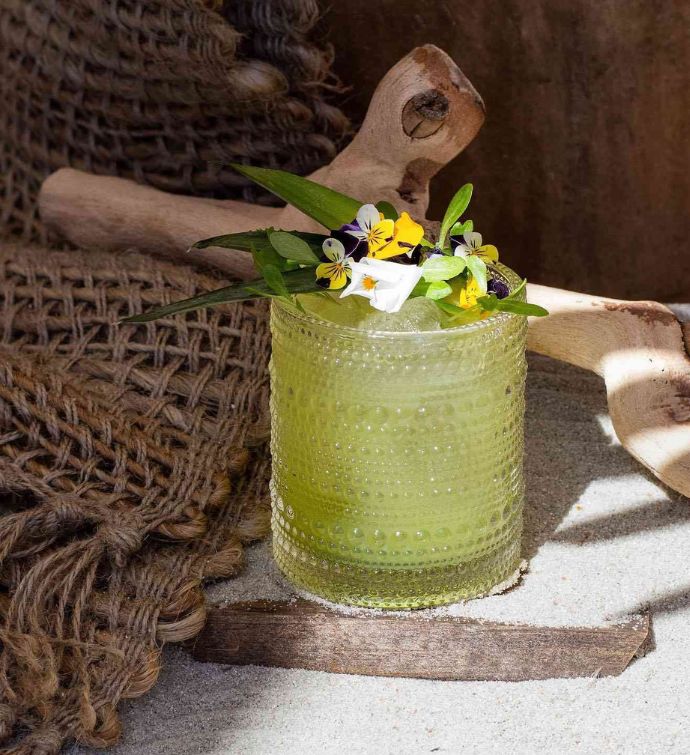 Green cocktail with flower garnish