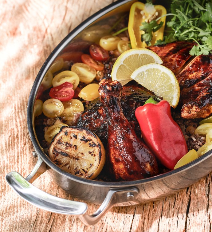 Pollo Asado dish with lemons, tomatoes and peppers in a metal pan