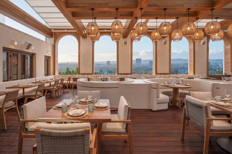 Airy rooftop restaurant Casa Madera at Mondrian Los Angeles with hanging wicker lights, large open windows and tables, chairs and couches