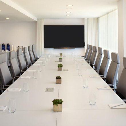 Conference room with long table, grey chairs and TV