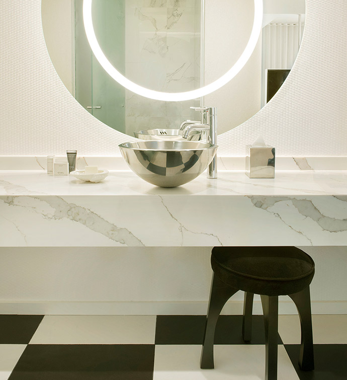 A black and white bathroom with a round mirror and a sink.