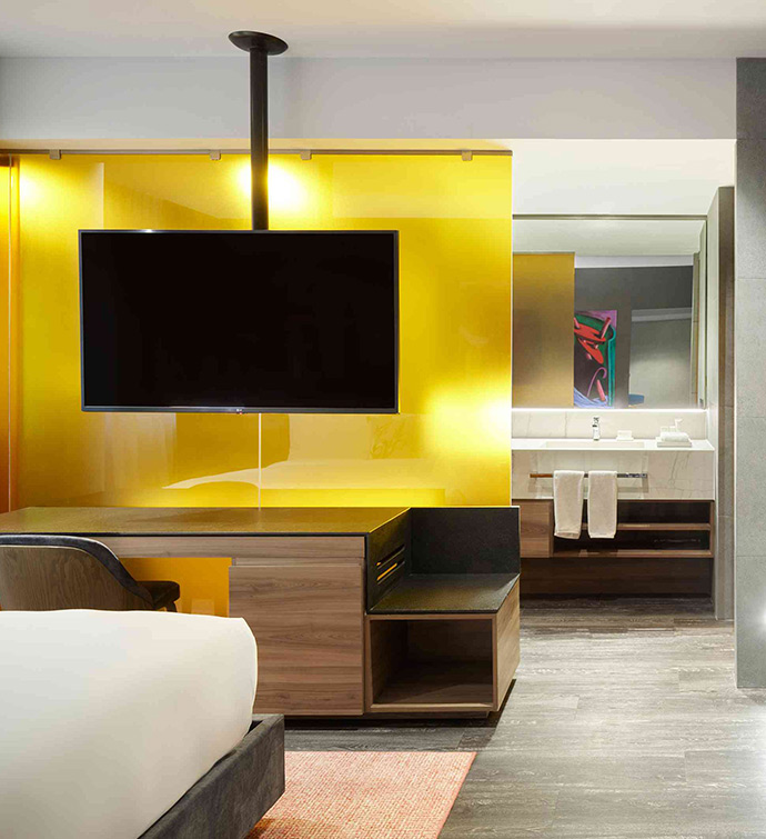 A cozy hotel room featuring a comfortable bed, a sleek desk, bathroom and a modern TV.