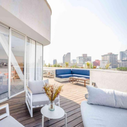 A balcony overlooking the city with white furniture.